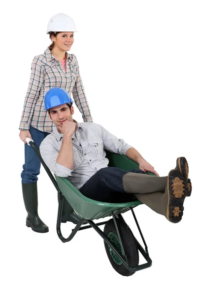 Craftswoman carrying a craftsman sitting in a wheelbarrow — Stock Photo, Image