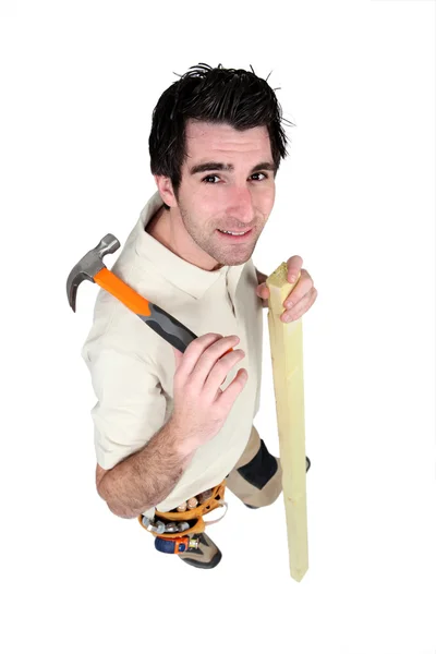 Carpenter stood with plank and hammer — Stock Photo, Image