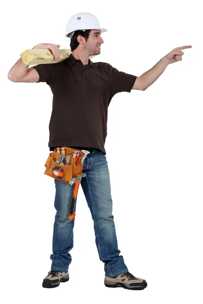 Carpenter in profile holding lumber pointing at someone — Stock Photo, Image