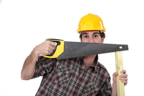 Tradesman hiding behind a saw — Stock Photo, Image