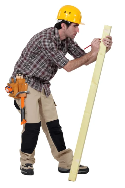Homem marcando uma medida em uma prancha de madeira — Fotografia de Stock