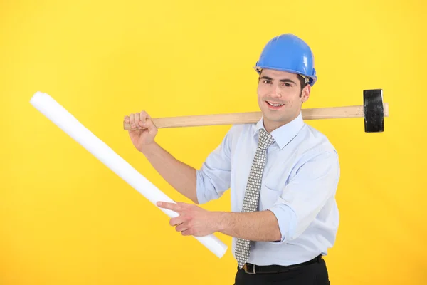 Ingenieur holding een samengevouwen blauwdruk en een hamer — Stockfoto