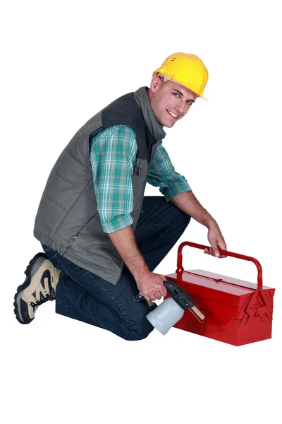 Artesanato segurando sua caixa de ferramentas e tocha de soldagem — Fotografia de Stock