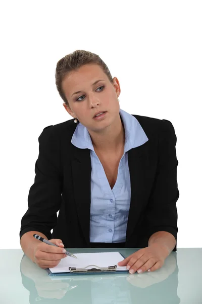 Mujer rubia sentada en el escritorio con sujetapapeles en blanco —  Fotos de Stock