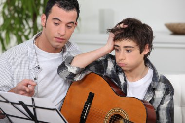 Man teaching to boy how to play guitar clipart