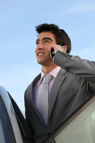 Businessman on the phone next to a car — Stock Photo, Image