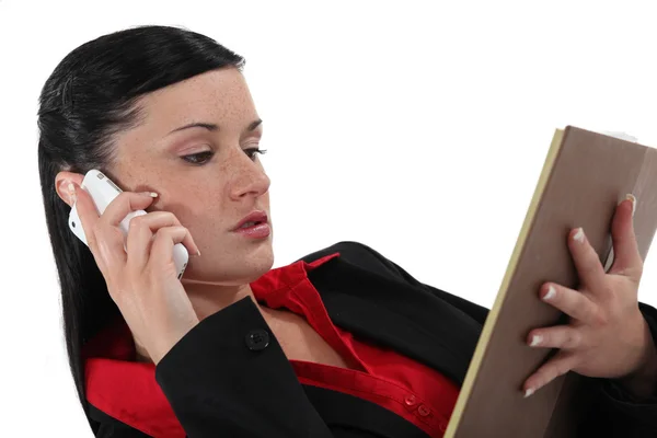 Brunette controleren details van telefoongesprek in dagboek — Stockfoto