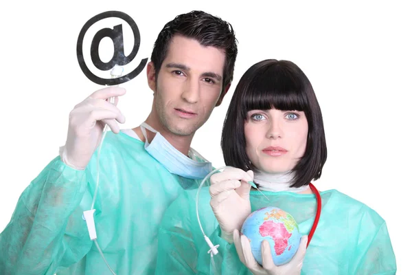 Medical professionals with at sign and globe — Stock Photo, Image