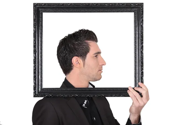 Young man holding a black frame — Stock Photo, Image