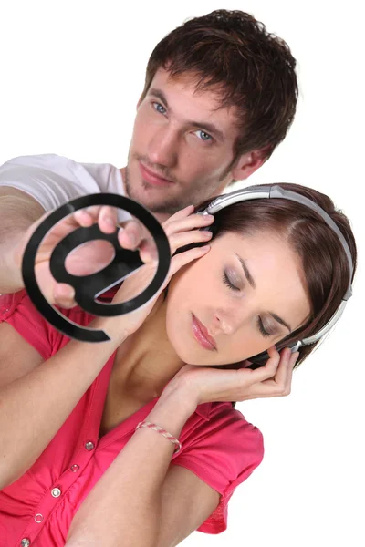 Mulher ouvindo música e um homem com um símbolo de at — Fotografia de Stock