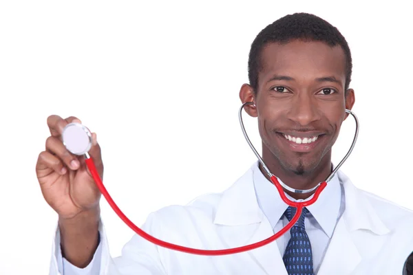 Médico sorridente segurando no alto seu estetoscópio — Fotografia de Stock