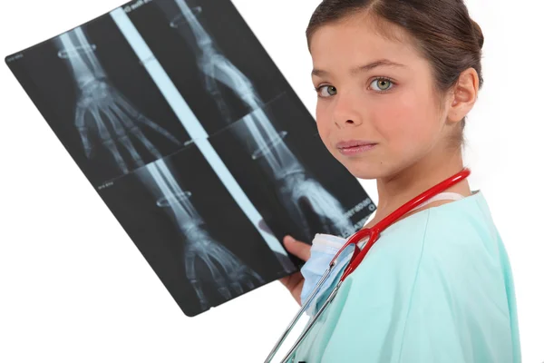 X 線のイメージを保持している看護婦として服を着た小さな女の子 — Stockfoto