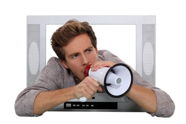 Man with a loud speaker leaning out of a TV frame — Stock Photo, Image