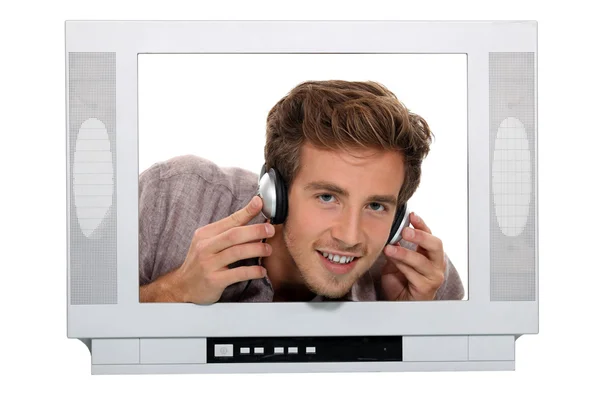 Hombre con auriculares detrás de la TV — Foto de Stock