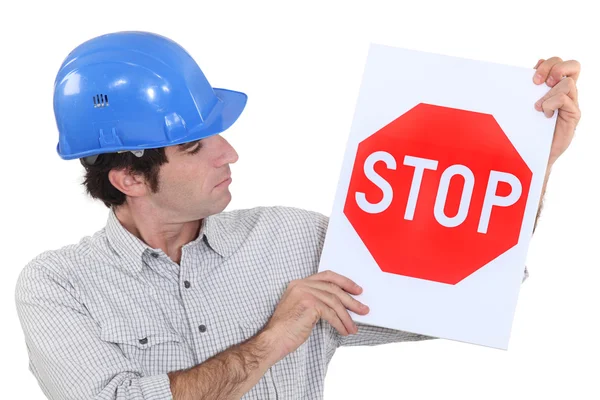 Homem usando um capacete e segurando um sinal de parada — Fotografia de Stock