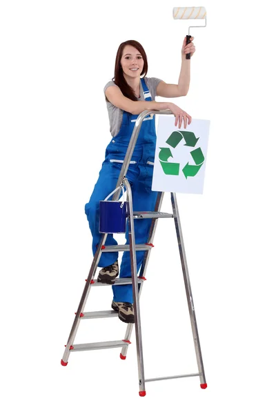 Tradeswoman holding a paint roller and a poster — Stock Photo, Image