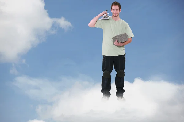 Montagem de um pedreiro sorridente em pé sobre uma nuvem — Fotografia de Stock
