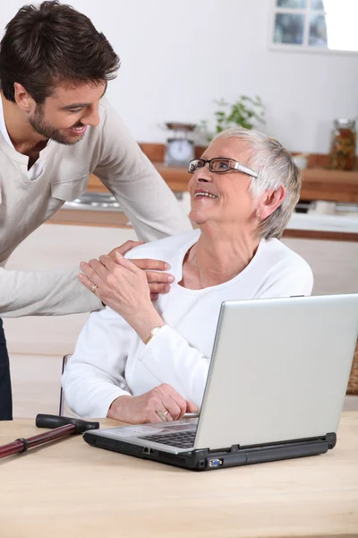 Hombre explicando a la mujer mayor cómo utilizar la computadora — Foto de Stock