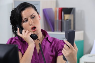 Annoyed receptionist answering ringing phones clipart