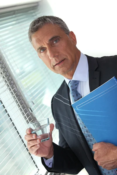 Podnikatel drží sklenici vody a složky — Stock fotografie