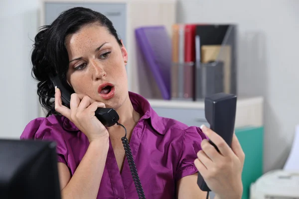 Geërgerd receptioniste beltoon telefoons beantwoorden — Stockfoto