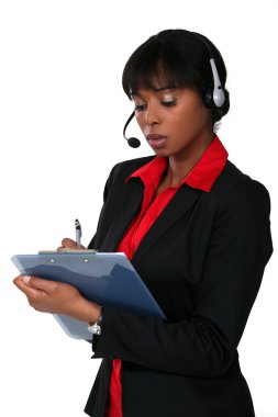 Woman wearing a headset and writing on a clipboard clipart