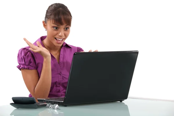 Kontorist tittar på hennes laptop i glee — Stockfoto