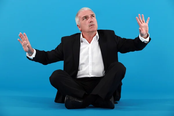 Mature businessman gesturing on blue background — Stock Photo, Image