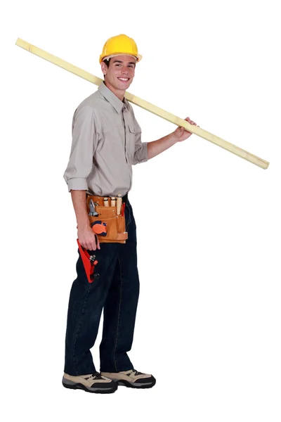 Studio omzunun üstünde tahta taşıyan genç marangoz — Stok fotoğraf