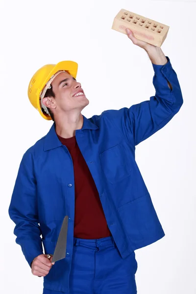 Молодой каменщик держит кирпич и лопату — стоковое фото