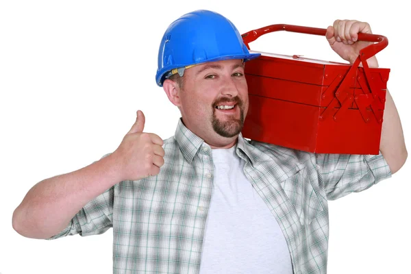 Comerciante carregando uma caixa de ferramentas e dando o polegar para cima — Fotografia de Stock
