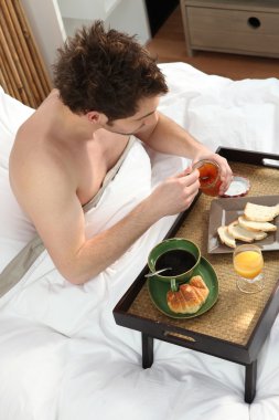 Man having breakfast in bed alone clipart