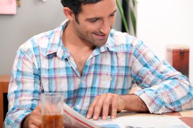 Man reading newspaper at the breakfast table clipart