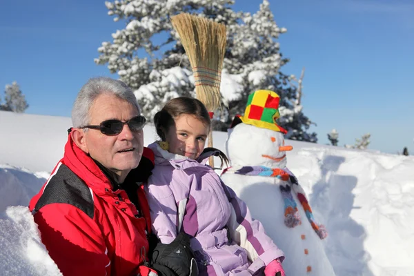 Батько і дочка стояли біля сніговика — стокове фото