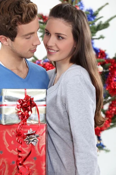 Genç adam hediye kız arkadaşına Noel için sunuyor. — Stok fotoğraf