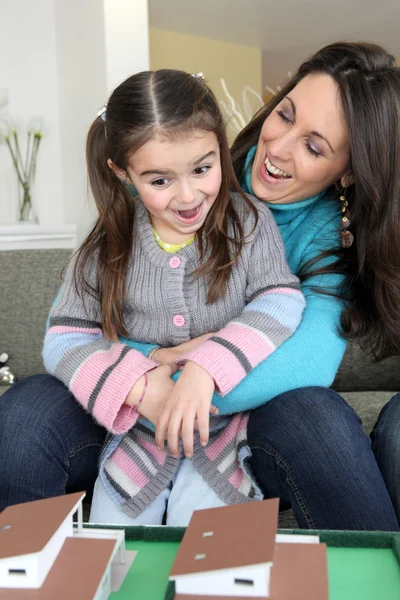 Gelukkig moeder en jonge dochter kijken naar huis model — Stockfoto