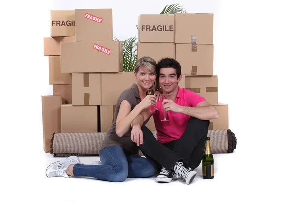 Couple surrounded by belongings and drinking champagne — Stock Photo, Image