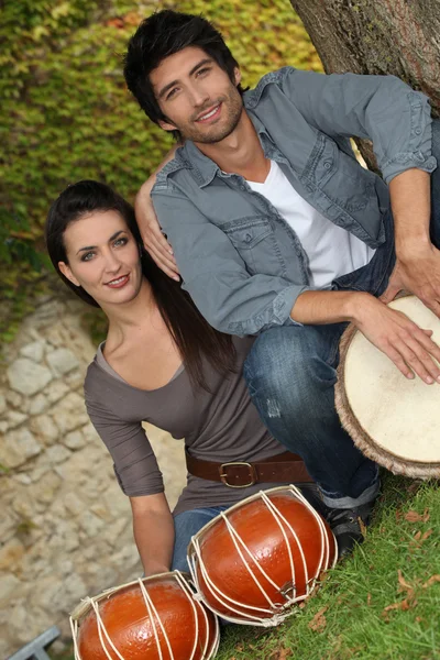 Пара, играющая на барабанах снаружи — стоковое фото