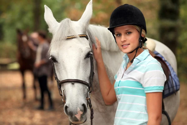 Девушка гладит белую лошадь — стоковое фото