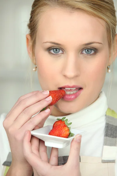 Blonde woman tasting strawberry — Stock Photo, Image