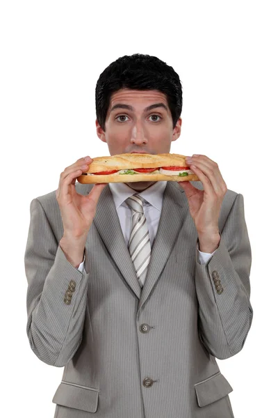 Businessman eating a yummy sandwich — Stock Photo, Image