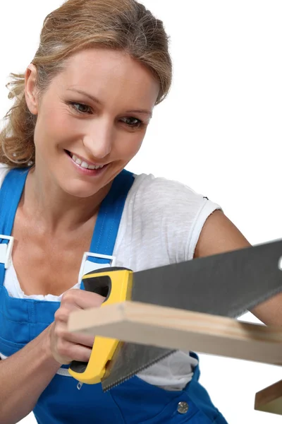 穿蓝色工作服锯切一块木板的女人 — 图库照片
