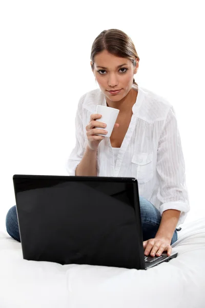 Chica bebiendo un té delante de la computadora portátil — Foto de Stock
