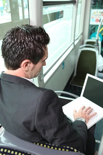 Zakenman in de bus die op zijn laptop werkt — Stockfoto