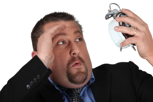 Businessman looking at his alarm clock in horror — Stock Photo, Image