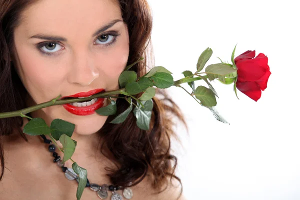 在她的嘴里拿着玫瑰的女人 — 图库照片