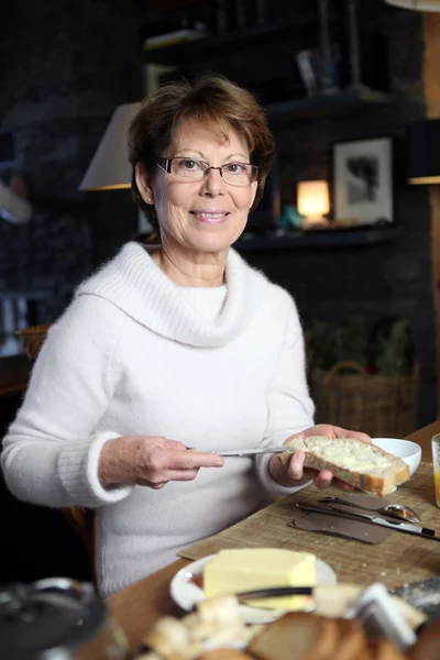 Mulher espalhando manteiga em um pedaço de pão — Fotografia de Stock
