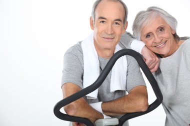 Senior couple doing exercises in the gym clipart