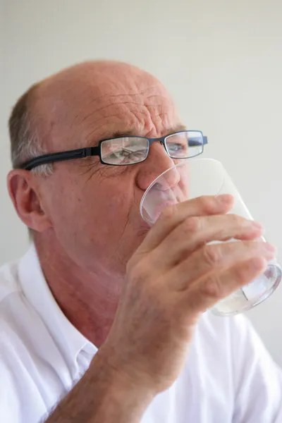 Ηλικιωμένος άντρας πίνει ένα ποτήρι νερό. — Φωτογραφία Αρχείου
