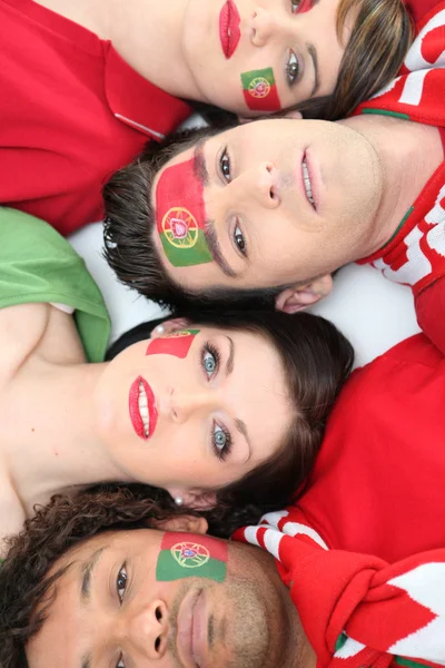 Four Portuguese soccer fans laying down together — Stock Photo, Image